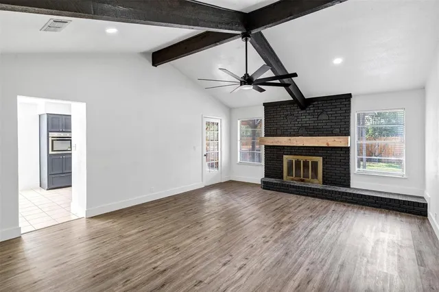 a view of an empty room with wooden floor fireplace and a window