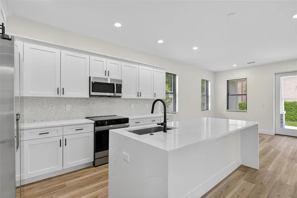 a kitchen with stainless steel appliances granite countertop a sink a stove top oven a counter space and cabinets