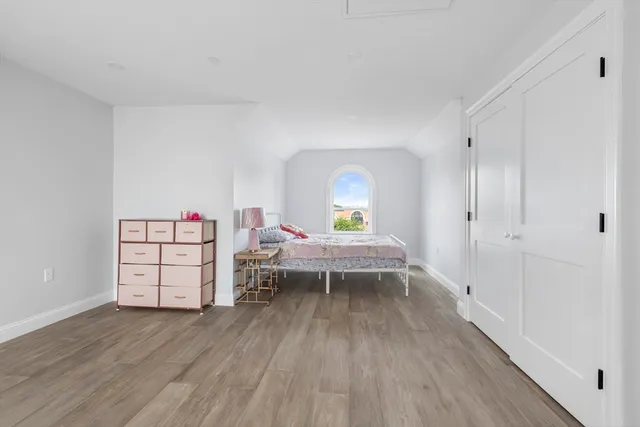 a view of a bedroom with baby crib and wooden floor