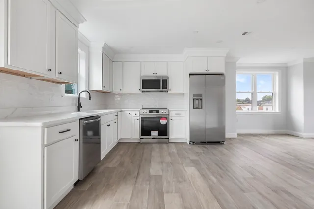 a kitchen with granite countertop a refrigerator stove and wooden floor