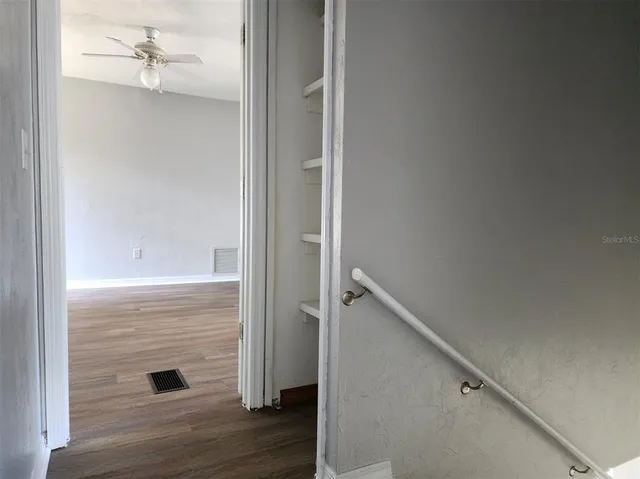 an empty room with wooden floor closet and windows