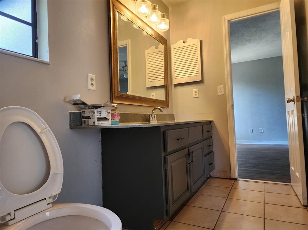 10911 Northwest 31st Place Gainesville, FL 32606 - Photo 21 of 27 a bathroom with a granite countertop toilet sink and mirror