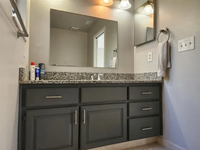 a bathroom with a granite countertop sink and mirror