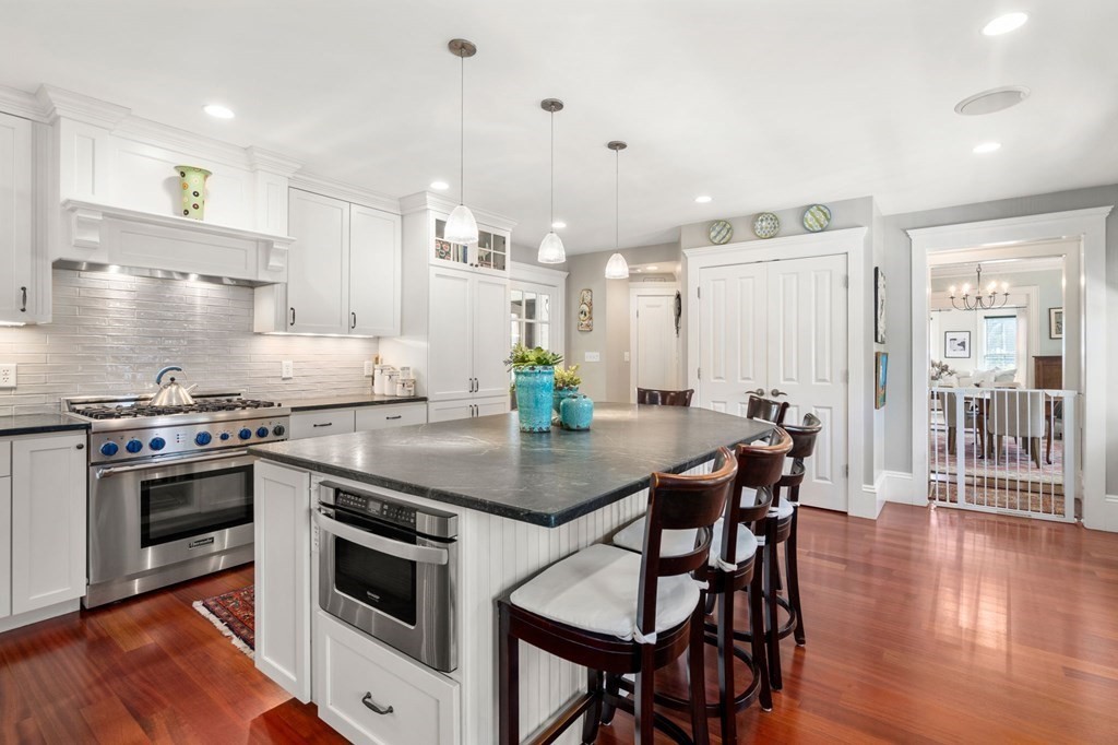 319 Sherman Street Canton, MA 02021 - Photo 5 of 29 a kitchen with stainless steel appliances granite countertop a stove a refrigerator a kitchen island a dining table and chairs with wooden floor