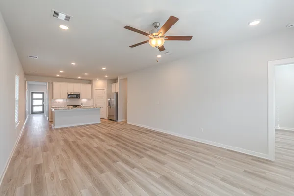 a view of a livingroom with a ceiling fan wooden floor and a ceiling fan