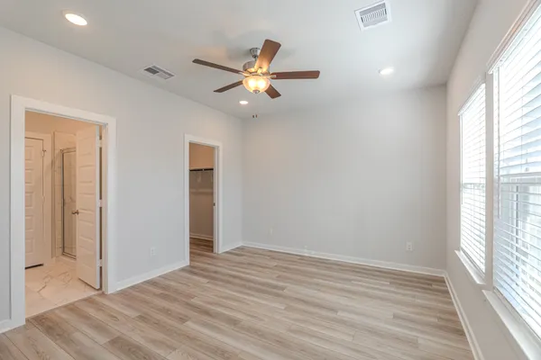 a view of empty room with wooden floor and fan