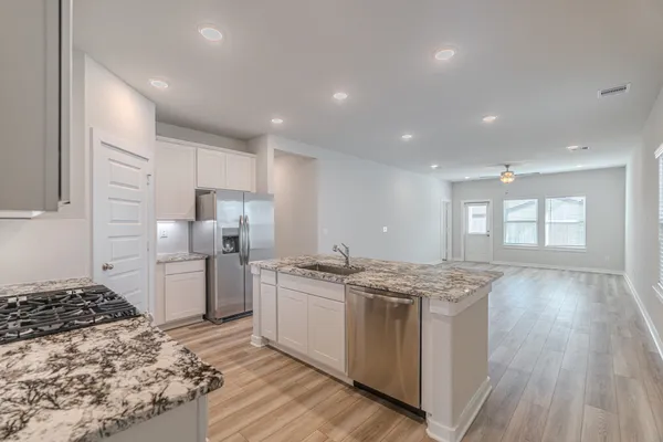 a kitchen with stainless steel appliances granite countertop a stove a sink dishwasher and a refrigerator