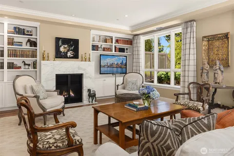 a living room with furniture two large windows and a fireplace