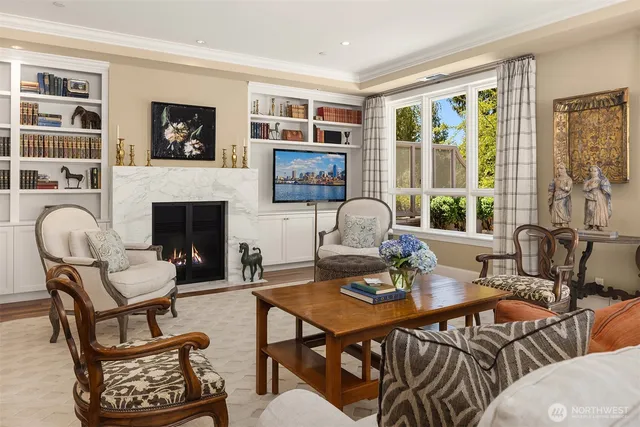 a living room with furniture two large windows and a fireplace