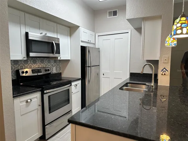 a kitchen with stainless steel appliances granite countertop a stove a refrigerator and a microwave