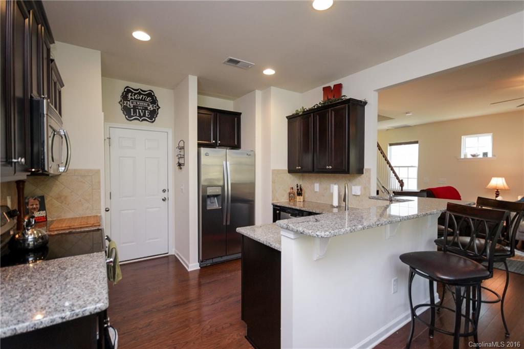 78126 Rillstone Drive, Unit 209 Lancaster, SC 29720 - Photo 6 of 24 a kitchen with stainless steel appliances granite countertop a refrigerator a sink a stove a dining table and chairs with wooden floor