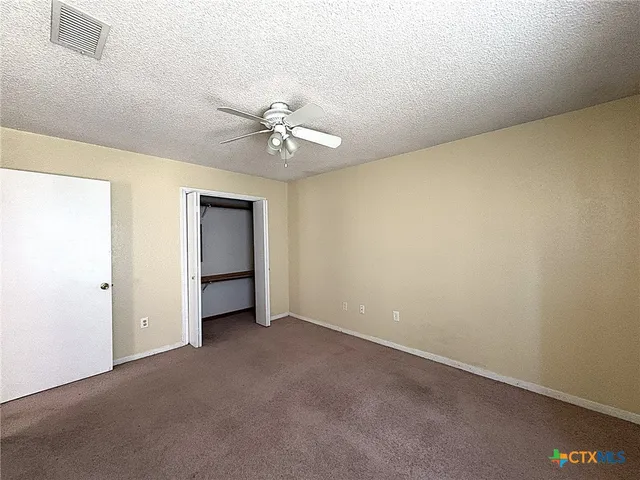 an empty room with a ceiling fan and a window