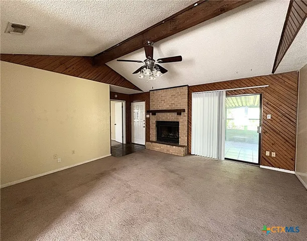 a view of an empty room with a fireplace and a window