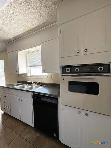a kitchen with granite countertop white cabinets and white appliances