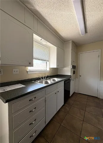 a kitchen with granite countertop a sink a stove and cabinets