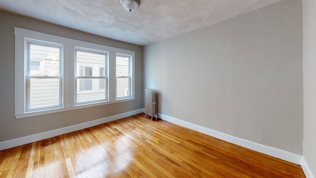 5 Edgar Terrace, Unit 2 Somerville, MA 02145 - Photo 2 of 6 a view of an empty room with wooden floor and a window
