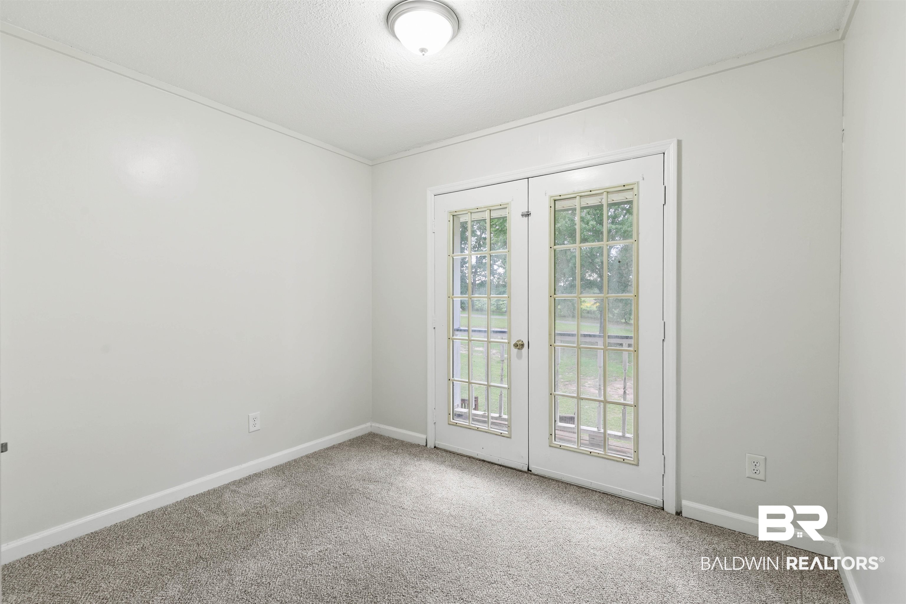 10420 Johnson Road South Mobile, AL 36695 - Photo 38 of 75 Room featuring double glass-paneled doors, neutral wall paint, gray carpet flooring, white baseboards, and a flush-mount ceiling light fixture