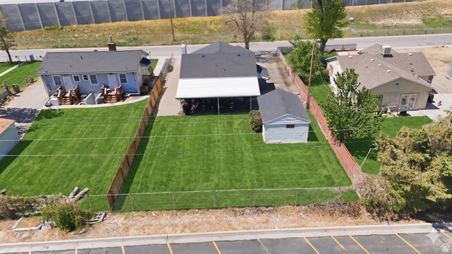7879 Oak Street Midvale, UT 84047 - Photo 26 of 32 Expansive fenced yard featuring a well-maintained lawn, accompanied by a detached structure and covered patio space