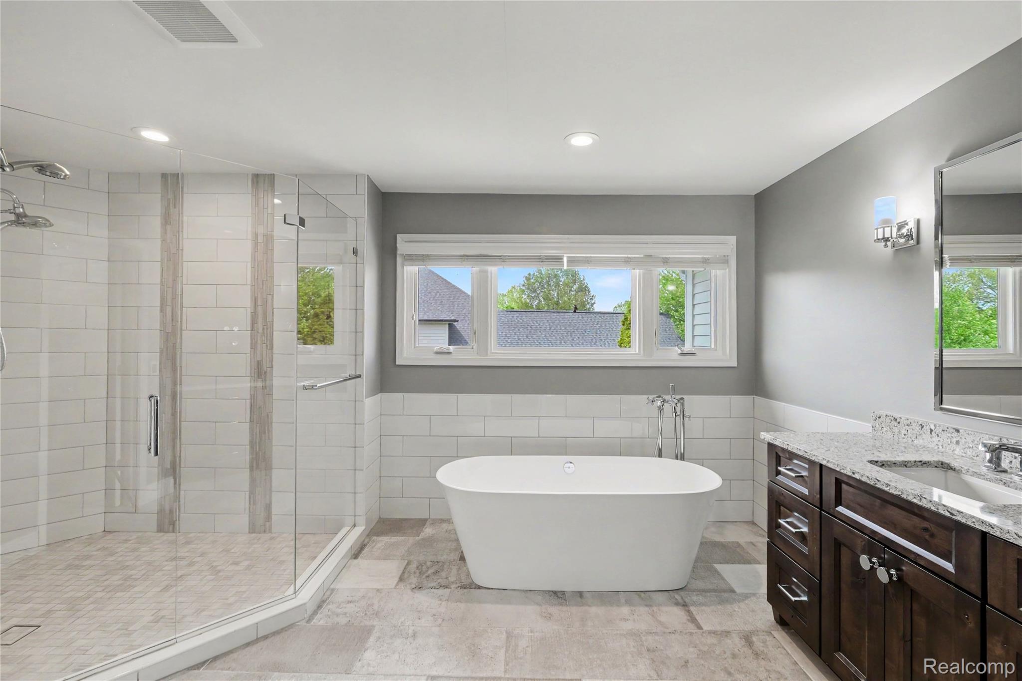 4179 St Andrews Street Howell, MI 48843 - Photo 32 of 75 Bathroom featuring vanity, a freestanding bath, a shower stall, wainscoting, and tile walls