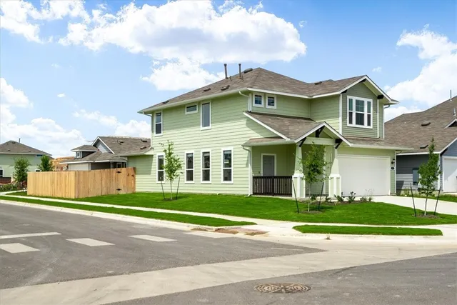 a view of a white house with a big yard and large trees