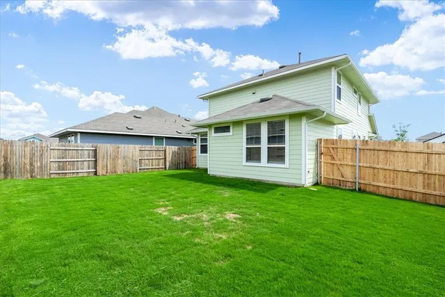 a view of a house with a yard and wooden fence