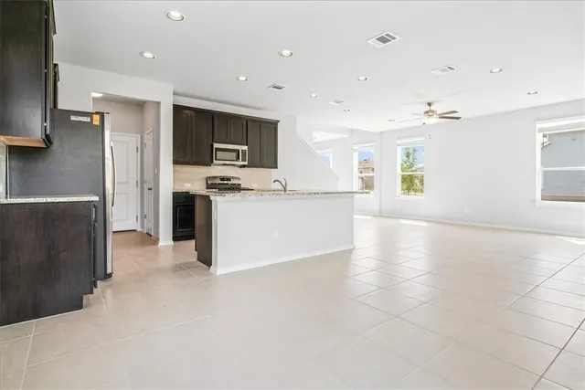 a large kitchen with stainless steel appliances a large counter top a stove a refrigerator and a sink