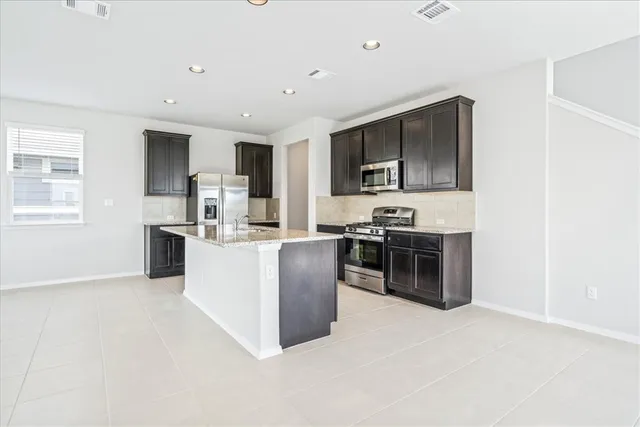 a kitchen with kitchen island stainless steel appliances a stove microwave and sink