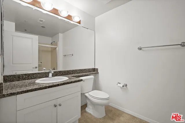 a bathroom with a granite countertop sink a toilet and a mirror