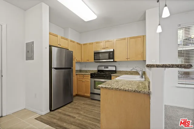 a kitchen with refrigerator a microwave a sink and cabinets
