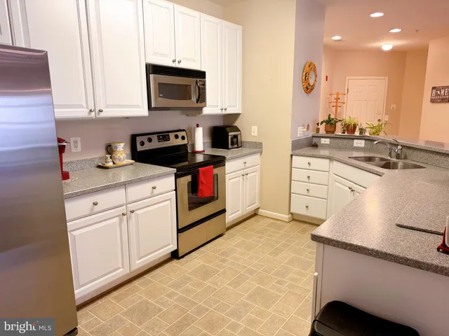 a kitchen with stainless steel appliances granite countertop a sink stove refrigerator and cabinets