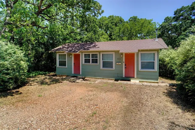 front view of house with a yard and trees all around