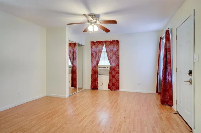 a view of empty room with wooden floor and fan