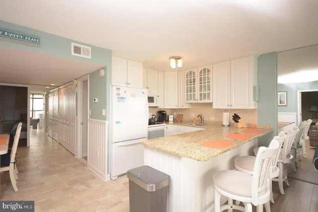 a kitchen with granite countertop a refrigerator a stove a dining table and chairs