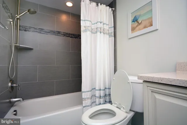 a bathroom with a granite countertop sink a toilet and shower