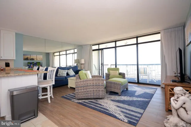 a living room with furniture large windows and wooden floor