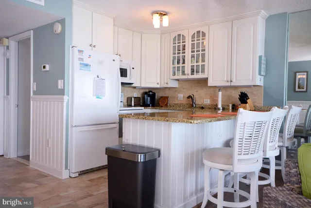 a kitchen with stainless steel appliances granite countertop a refrigerator a sink a stove a dining table and chairs