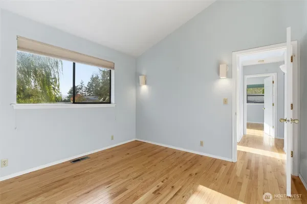 a view of empty room with wooden floor and fan