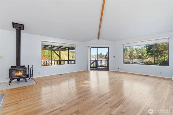 a view of an empty room with window and wooden floor