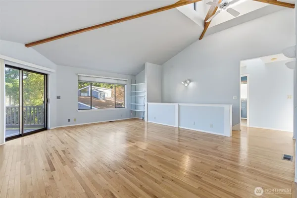 a view of an empty room with wooden floor and a window