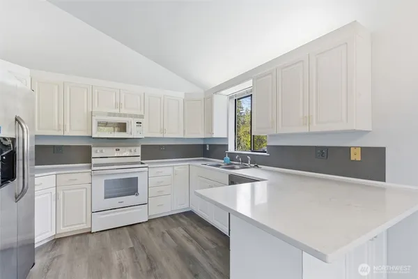 a kitchen with granite countertop white cabinets and white appliances