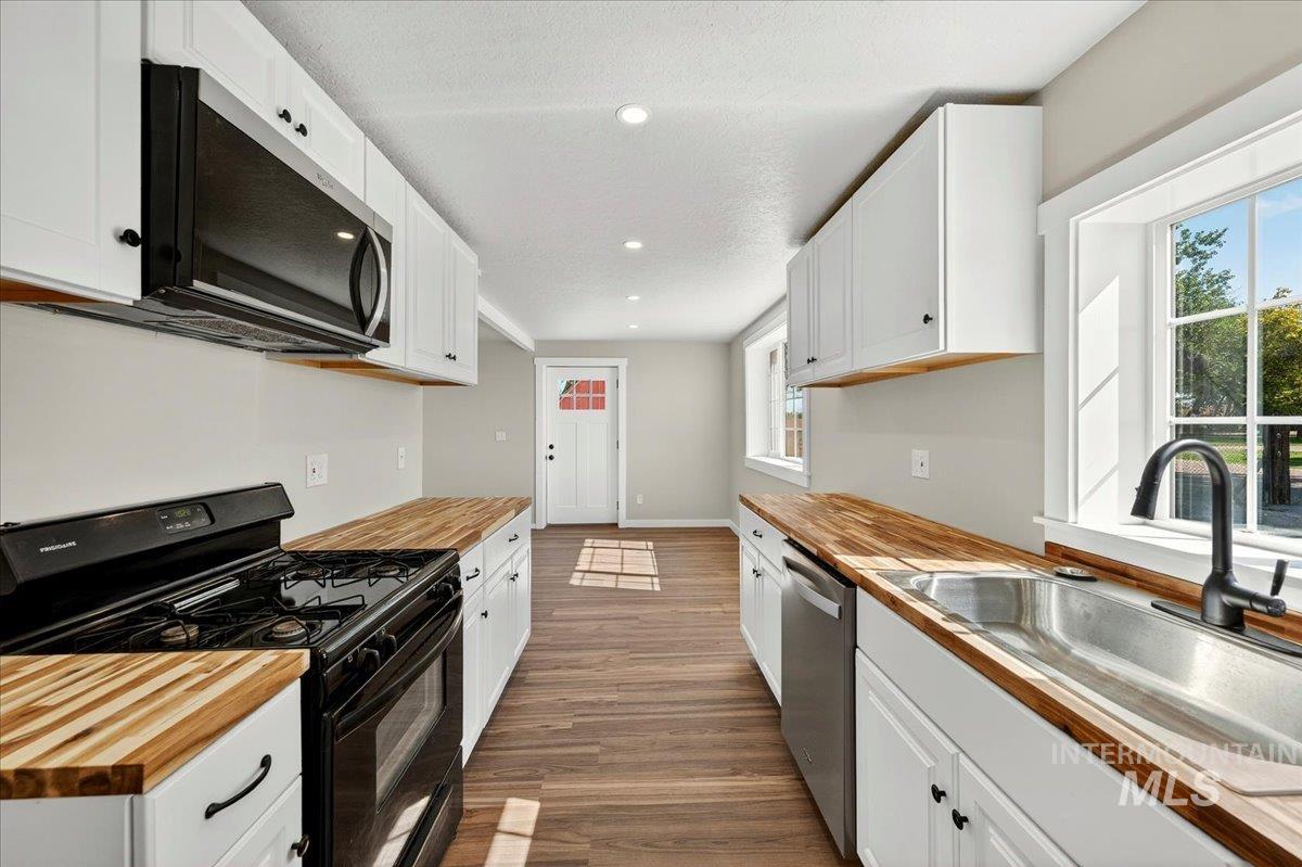 109 Parma Road Parma, ID 83660 - Photo 11 of 31 Kitchen featuring all new white cabinetry, wood-finish countertops, and luxury plank flooring