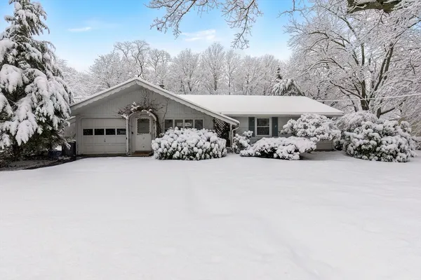 a view of a white house covered with snow in the yard