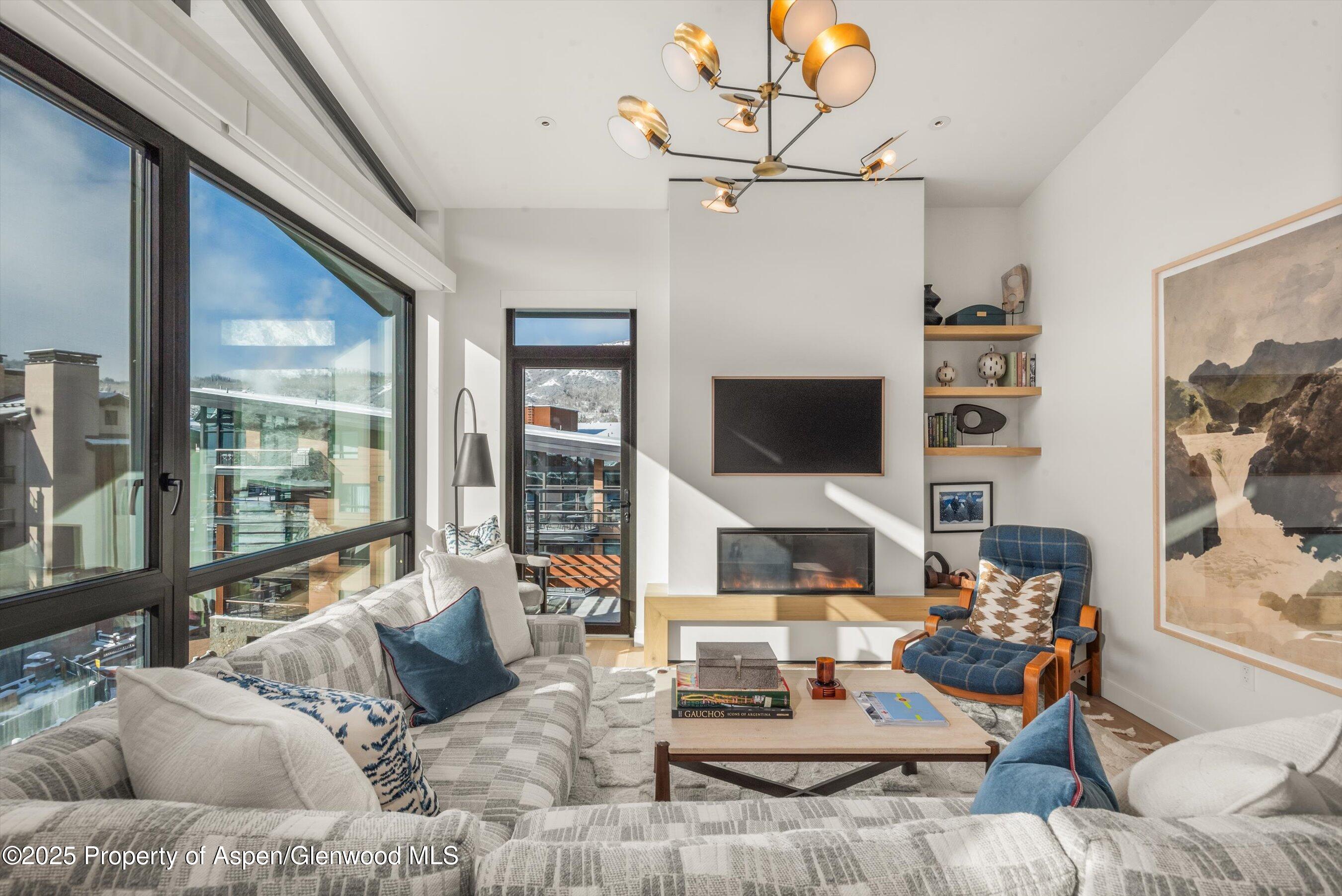 119 Wood Road, Unit 601 Snowmass Village, CO 81615 - Photo 1 of 20 a living room with furniture a flat screen tv and a floor to ceiling window
