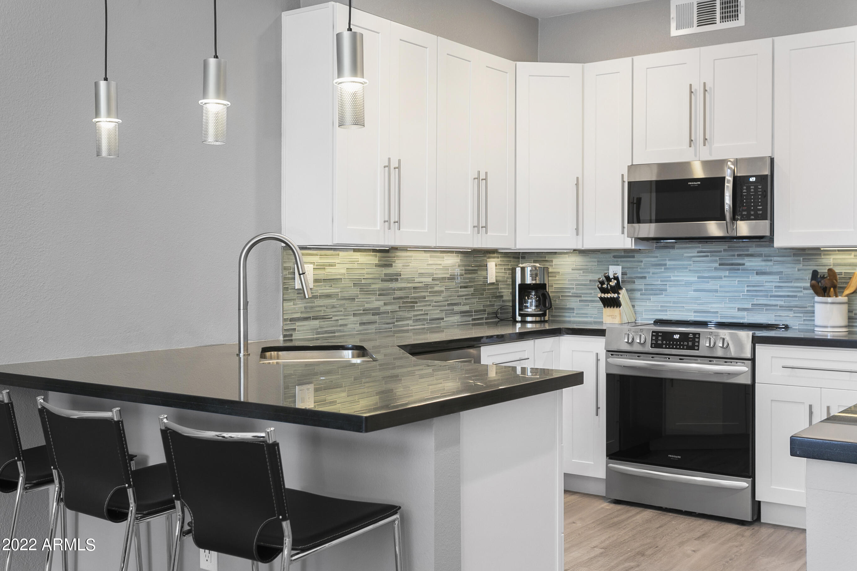 7700 East Gainey Ranch Road, Unit 206 Scottsdale, AZ 85258 - Photo 3 of 33 a kitchen with stainless steel appliances granite countertop a sink stove and microwave