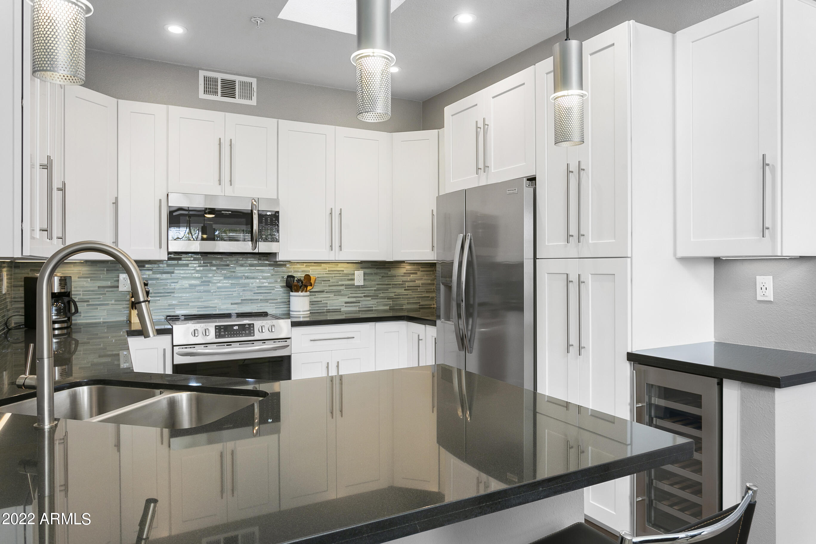 7700 East Gainey Ranch Road, Unit 206 Scottsdale, AZ 85258 - Photo 5 of 33 a kitchen with stainless steel appliances granite countertop a refrigerator a stove and a sink with wooden floor