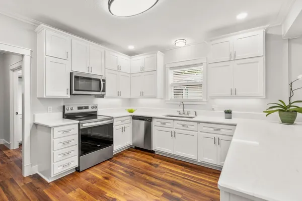 a kitchen with granite countertop a sink cabinets stainless steel appliances and a counter space