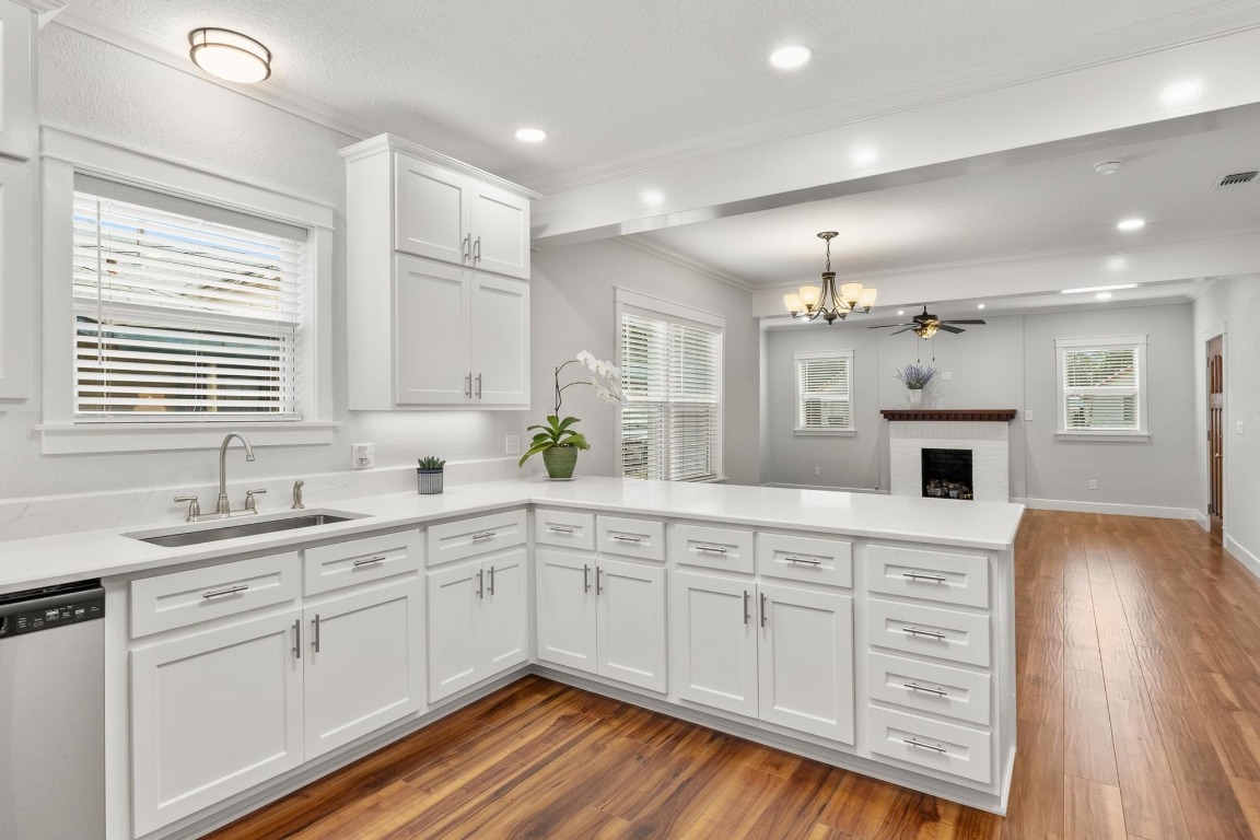 522 South Walnut Avenue Luling, TX 78648 - Photo 13 of 33 a kitchen with a sink dishwasher a stove and white cabinets with wooden floor