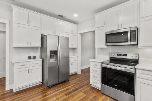 a kitchen with cabinets stainless steel appliances and wooden floor