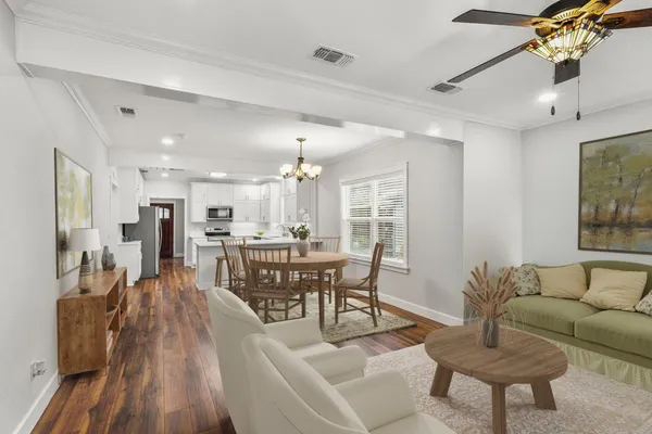a living room with furniture and a dining table with wooden floor