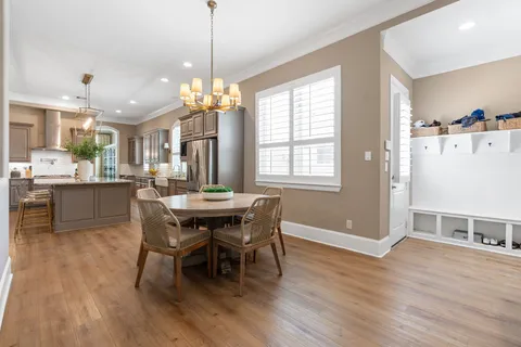 a dining room with wooden floor a chandelier a wooden table and chairs